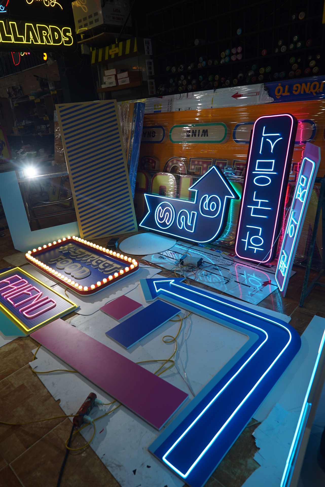 Đèn neon trang trí cửa hàng tiện lợi S26 tại Thanh Hoá 3 Cụm biển neon gồm mũi tên xanh, bảng chỉ dẫn đứng và dây điện đặt trên bàn xưởng