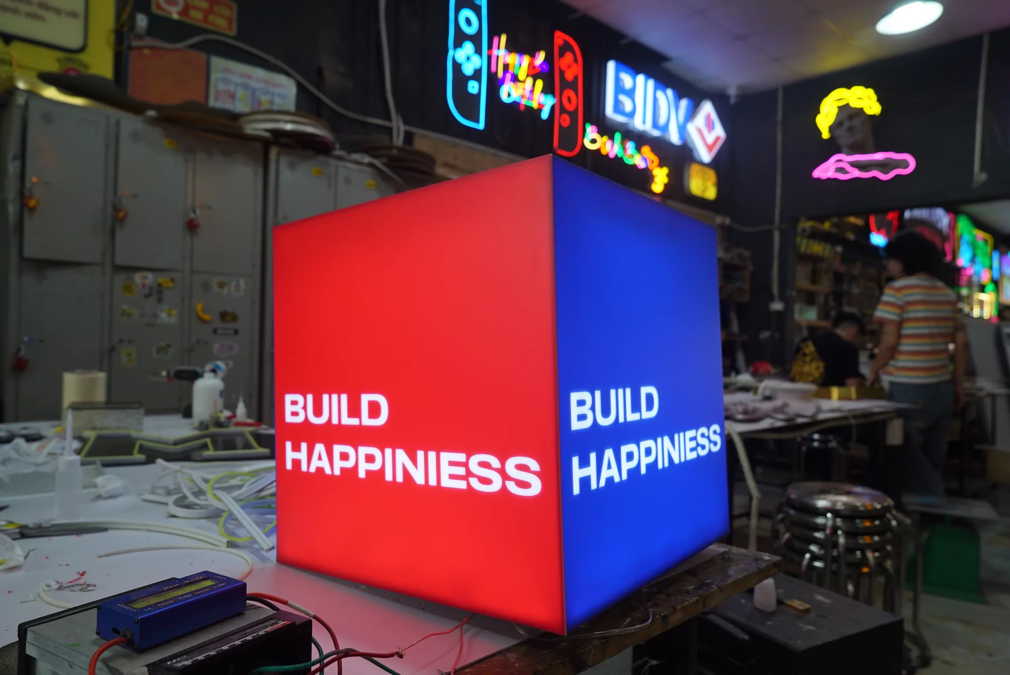 Hộp đèn quảng cáo: 5 loại phổ biến và cách chọn cho mặt tiền 2 Hộp đèn quảng cáo Build Happiness hai mặt đang phát sáng tại xưởng